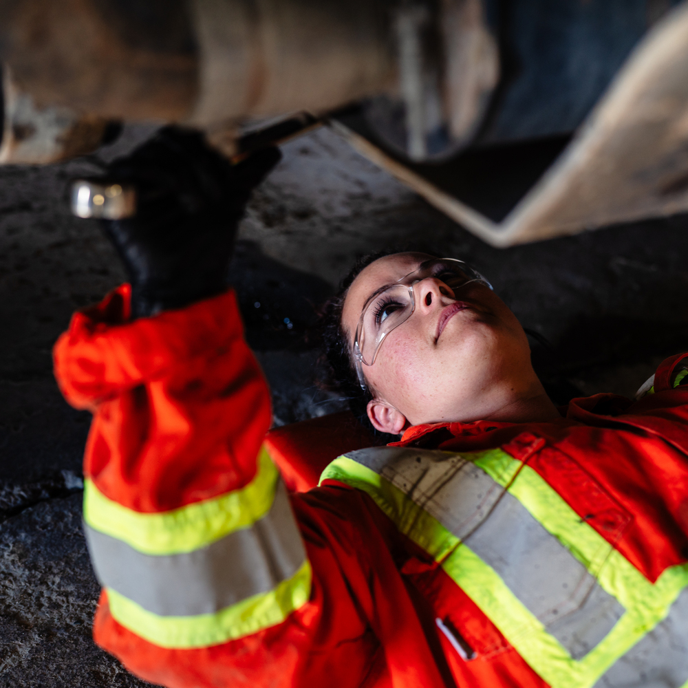 Femme qui inspecte un dessous d'un véhicule